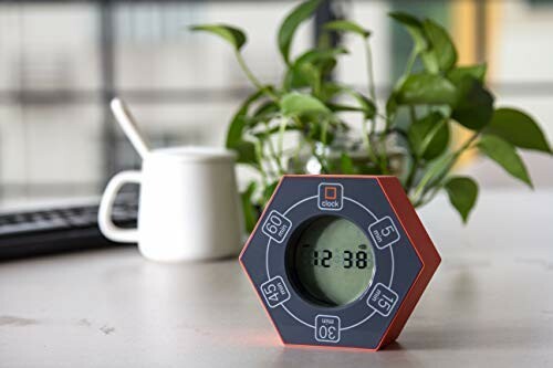 Hexagonal digital timer on a table with a plant and mug in the background.